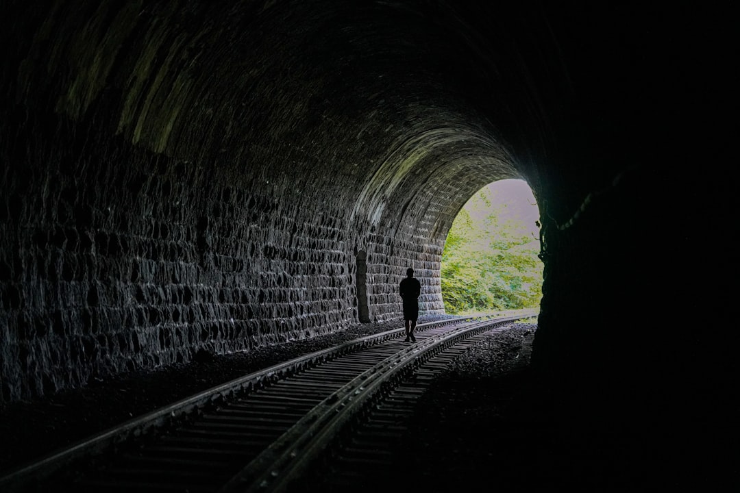 A person walking into a dark tunnel with a light at the end